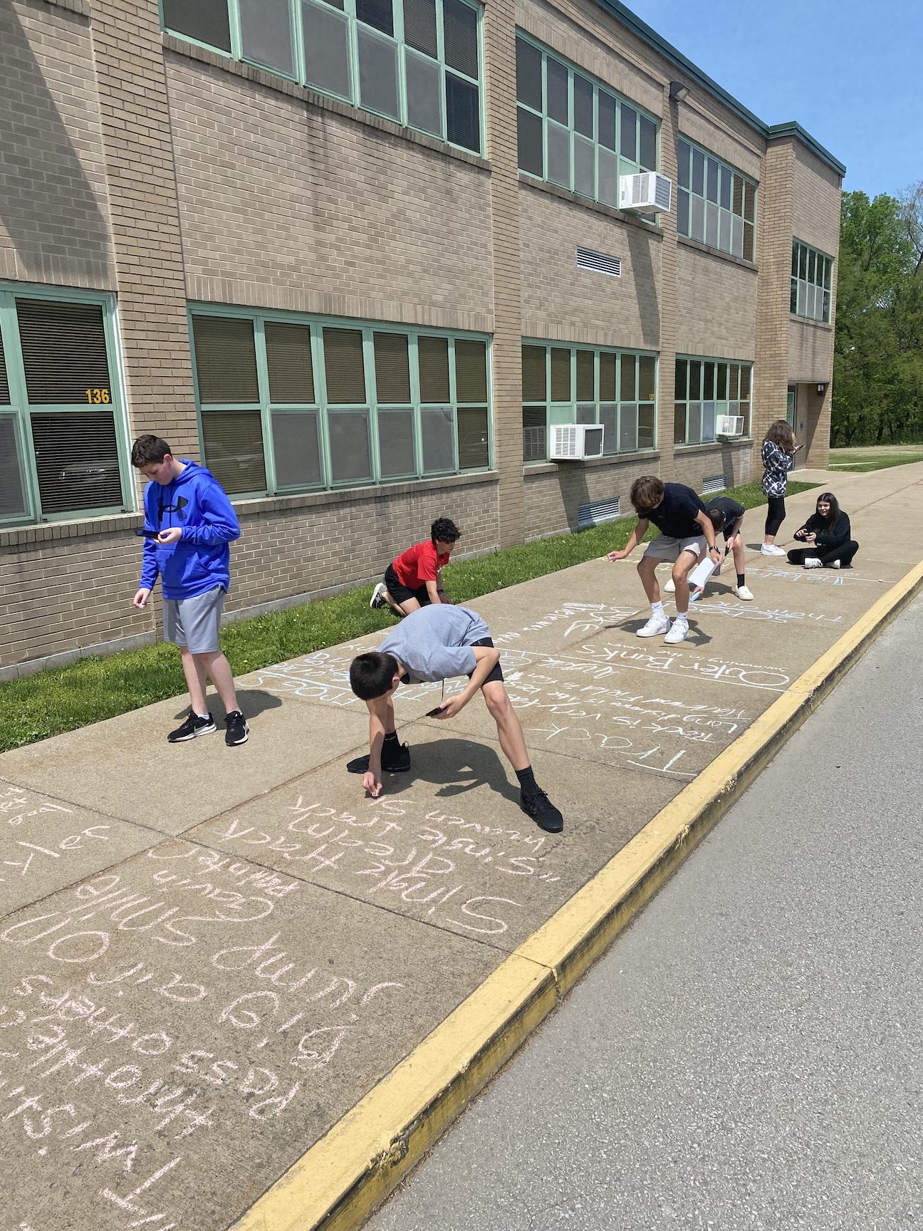 The students write their haiku poems with chalk